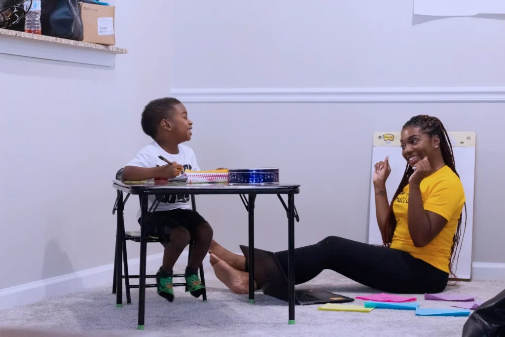 A woman sitting on the ground teaching a child